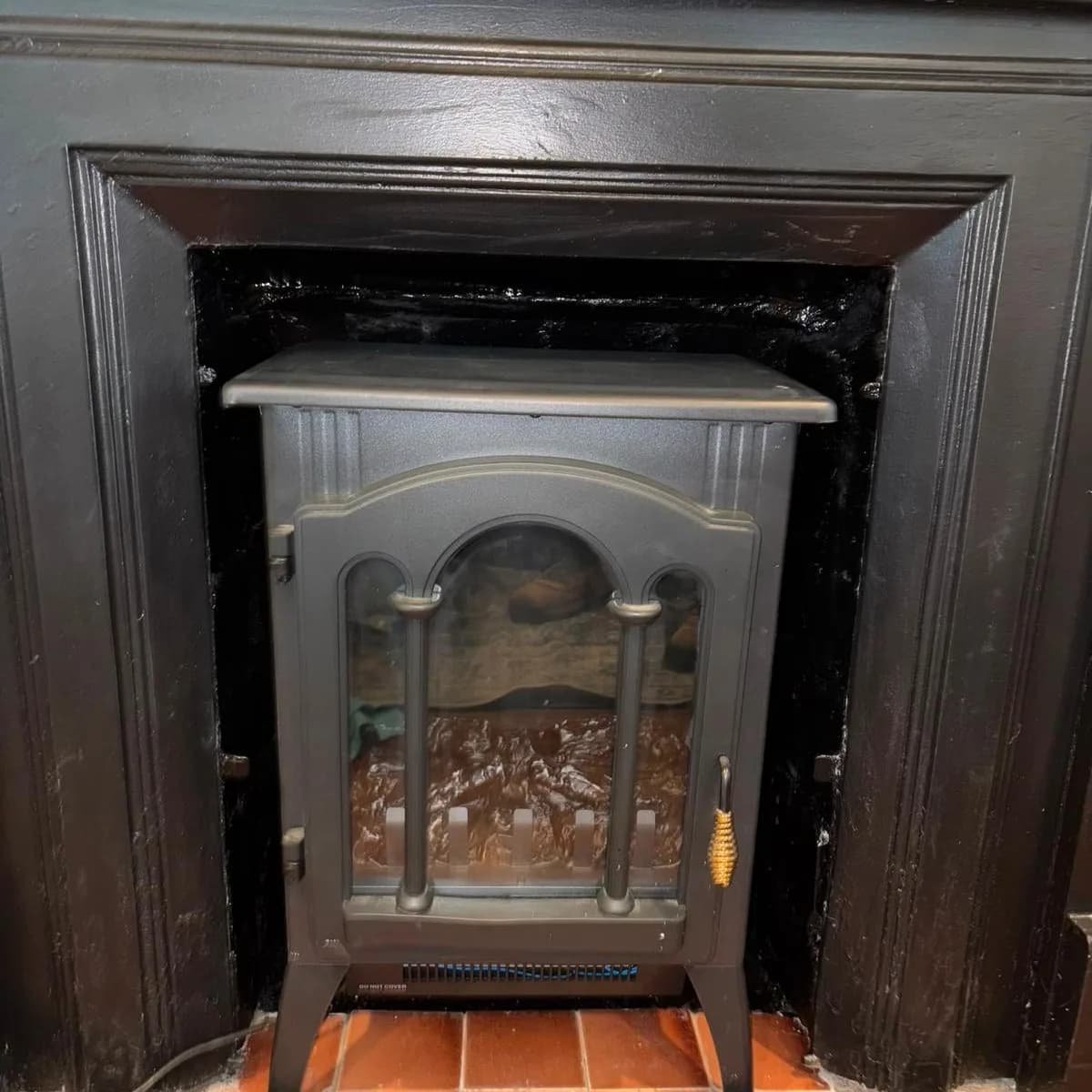 After: A fireplace opening masked with painter's tape and its sooty firebrick exposed, and the same opening finished with a stove standing in it