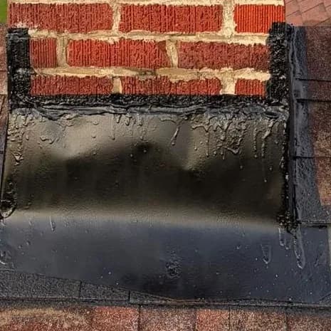 New black chimney flashing sealed where the brick meets the roof shingles