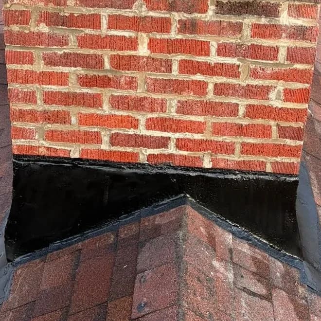 Chimney flashing sealed continuously around the corner where two roof slopes meet the brickwork