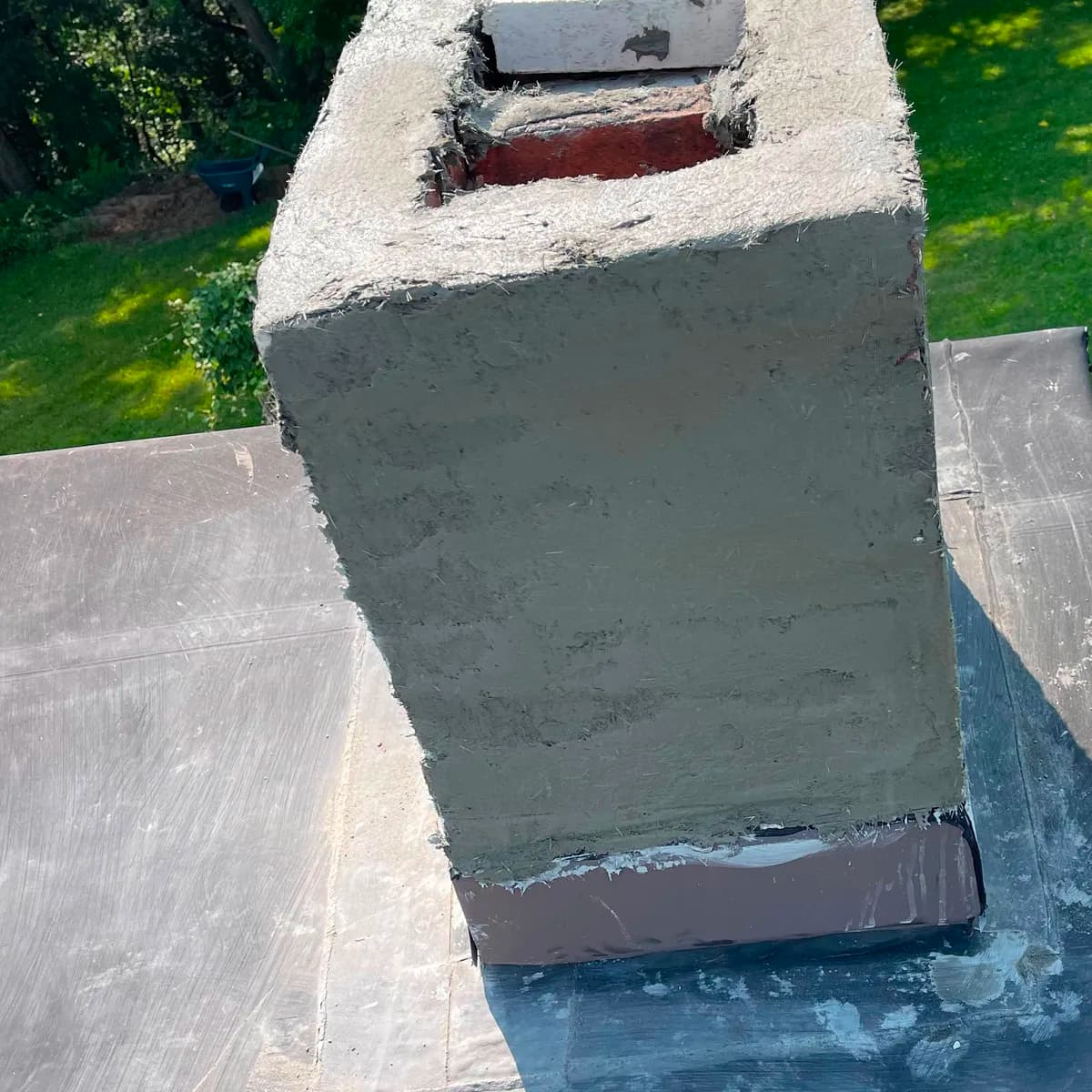 After: A loose chimney crown edge lifting away from deteriorated brick, and the upper chimney rebuilt with a continuous parged exterior