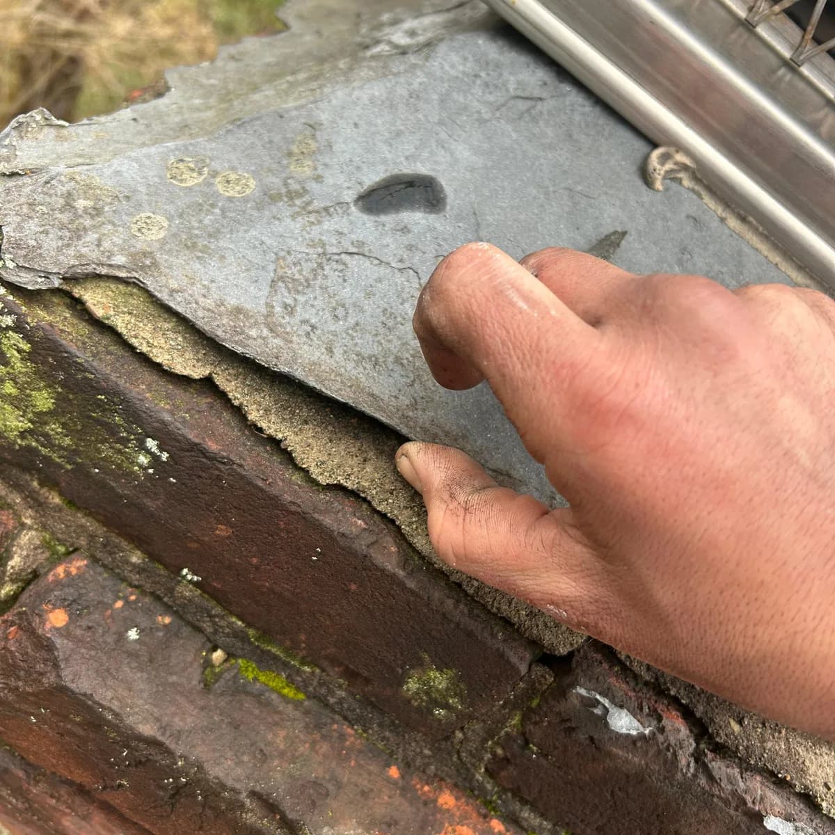 Before: A loose chimney crown edge lifting away from deteriorated brick, and the upper chimney rebuilt with a continuous parged exterior