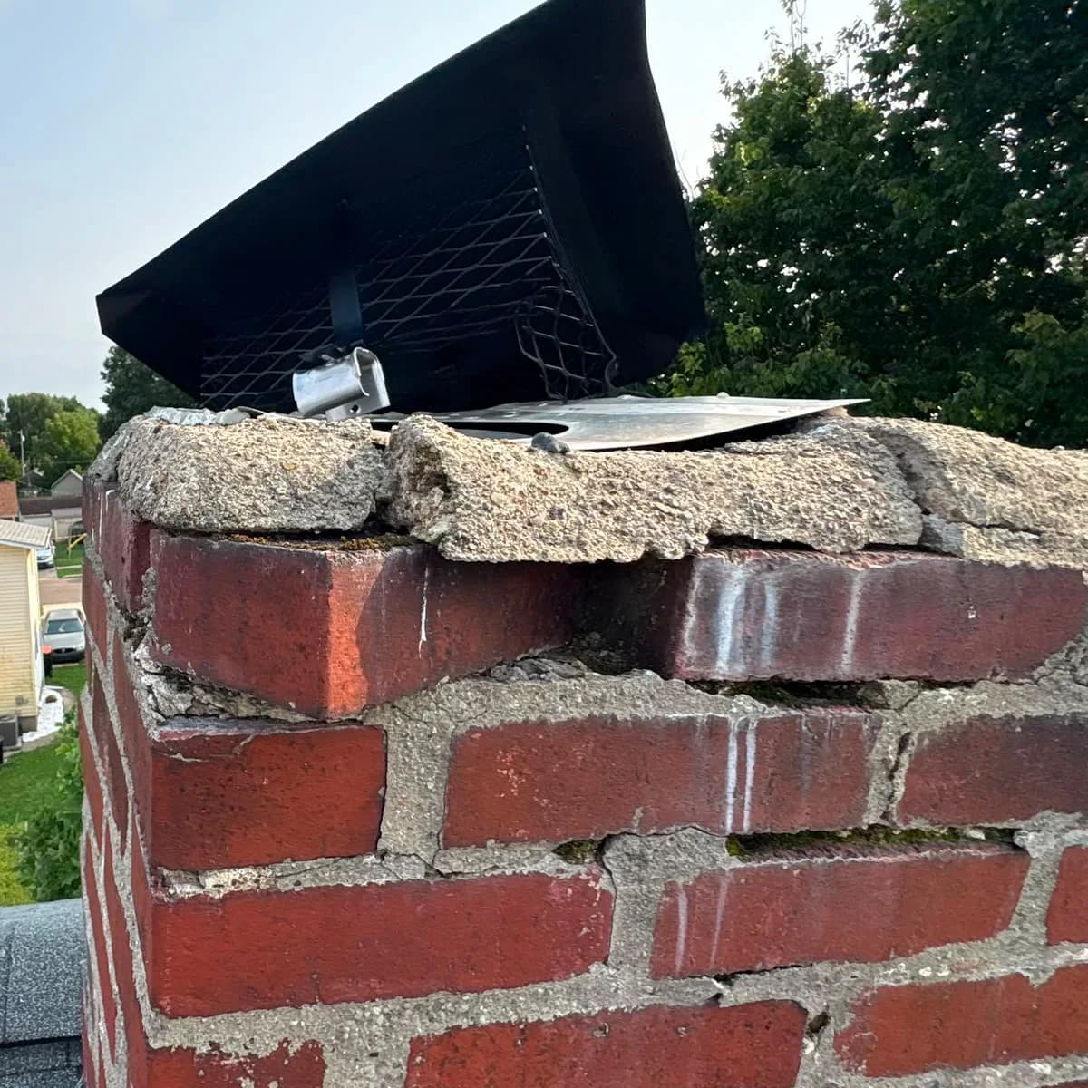 Before: A broken chimney crown beneath an old metal hood, and the same brick stack with a rebuilt crown and two capped metal flues