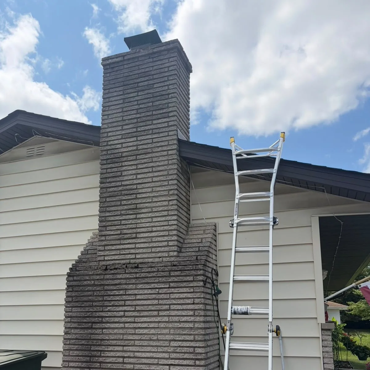 Tall exterior chimney before the masonry finish, with weathered joints visible on the face